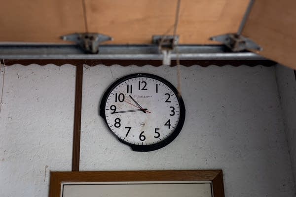 A broken clock hangs on a garage wall