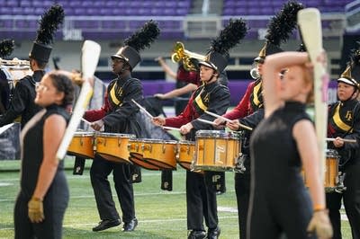 A marching band performs on the field of a football stadium.