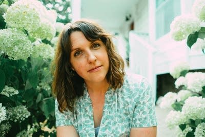 A woman sits in a garden of hydrangeas