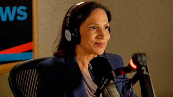 A woman sits in a radio studio.