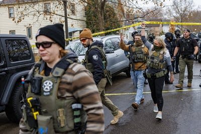 Officers walk under police tape.