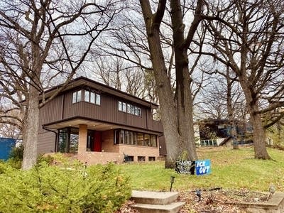 a modern brown home behind trees