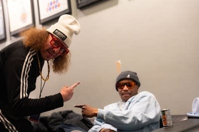 Two artists pose together for a photo backstage at a music venue
