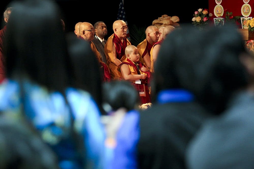 Monks and lamas stand to honor the Dalai Lama.