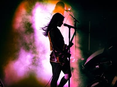 A musician plays guitar onstage in a music venue
