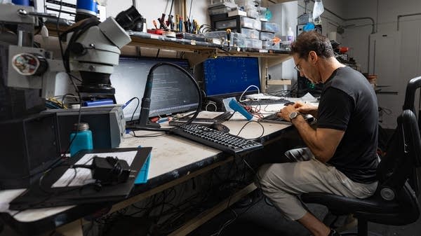 Del Jaljaa works on a laptop motherboard at his repair bench. Right to Repair advocates warn that Microsoft’s move away from Windows 10 could create mountains of electronic waste.