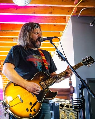 A musician sings and plays guitar in a small music venue