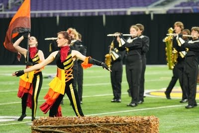 A marching band performs on the field of a football stadium.