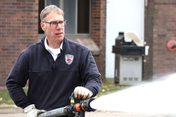 A man sprays fire-suppressant foam out of a firehose.
