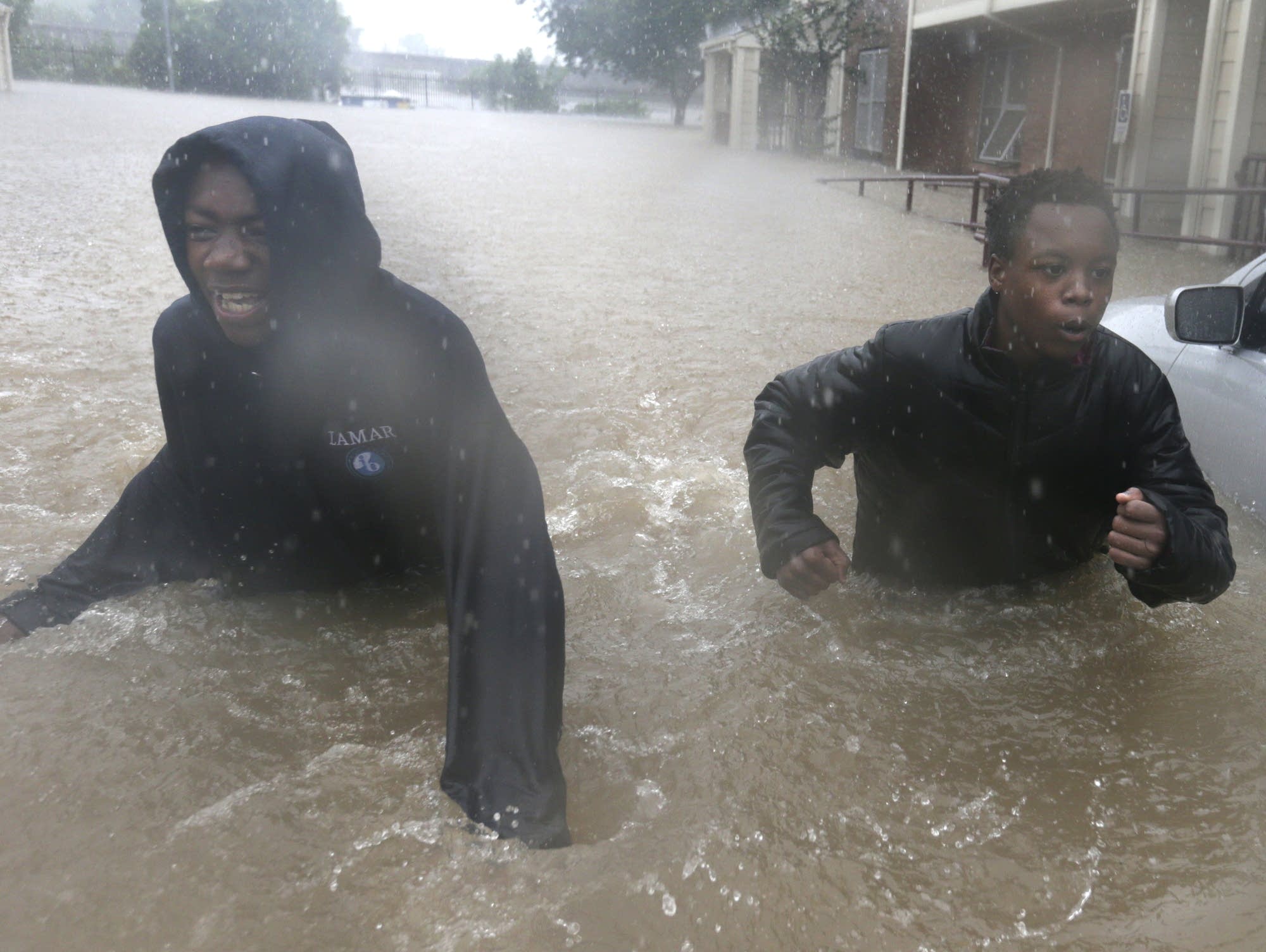 Two friends make their way through floodwaters.