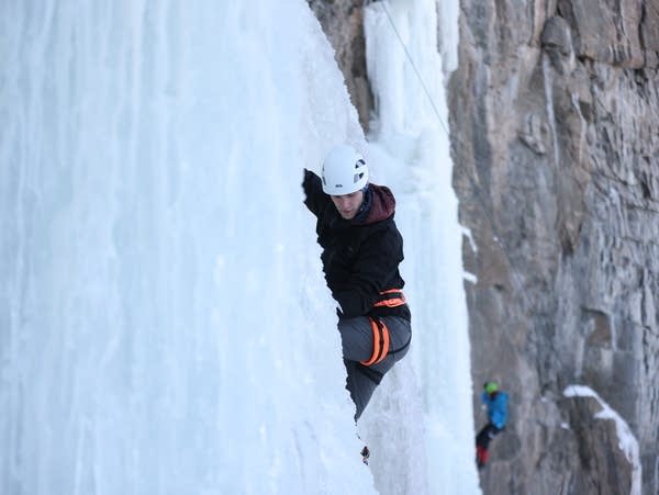 A person scales an icy wall