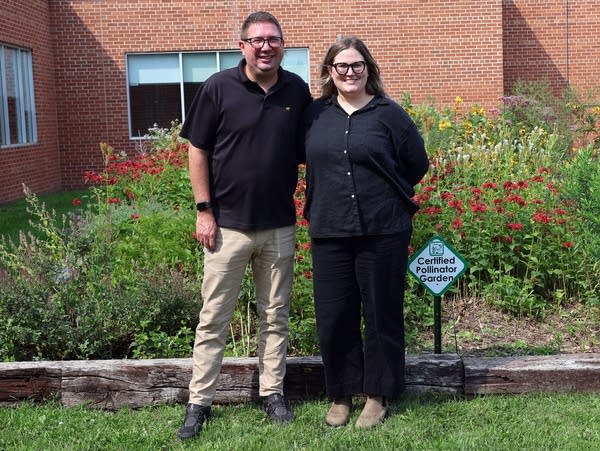 two people stand in front of a flower garden 