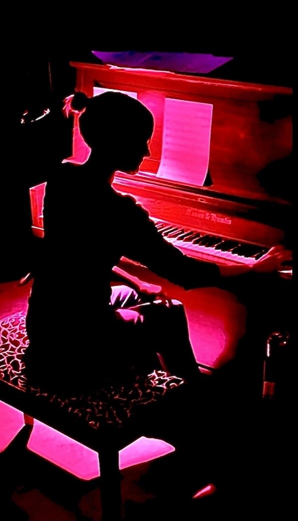 A woman plays piano in a dark cinema to accompany a silent film
