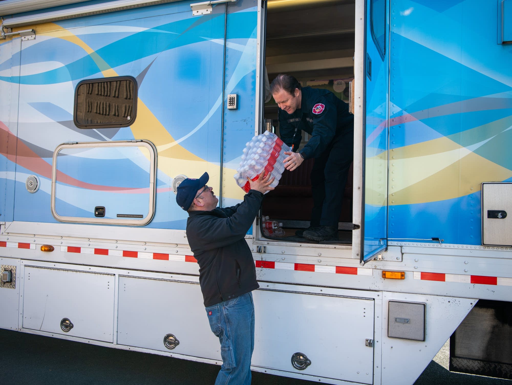 Eric Zimmerman, left, and Greg Hayes load water in a mobile clinic