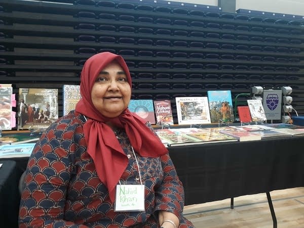 A woman sits by a display at a book fair