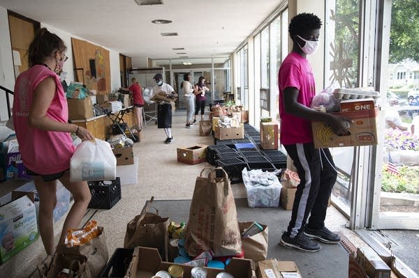 A group of people carry boxes of food. 