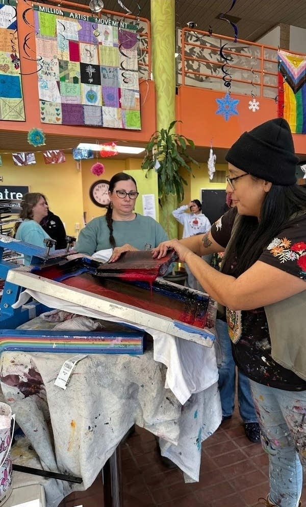 People gather in an artist workspace to work on screen-printing.