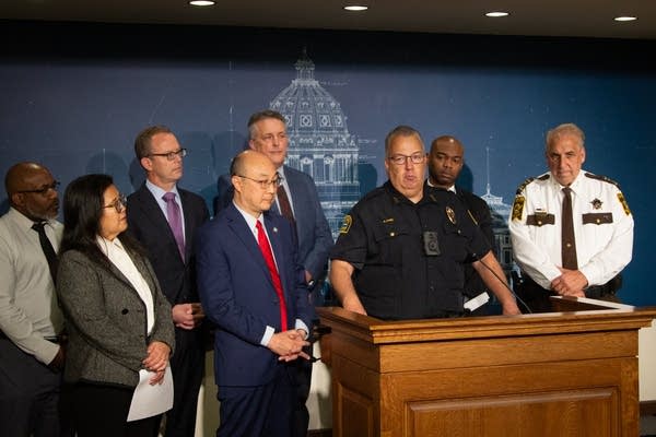 A person speaking at a podium with multiple people behind him2