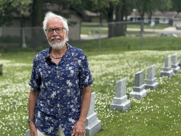 A man stands near a row of gravestones.