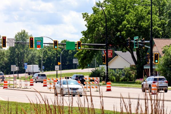 A collection of cars travel on a road with detour signs.