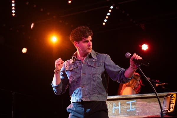 A man dances next to a piano during an onstage performance