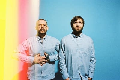 Two men in Oxford cloth shirts pose for a portrait