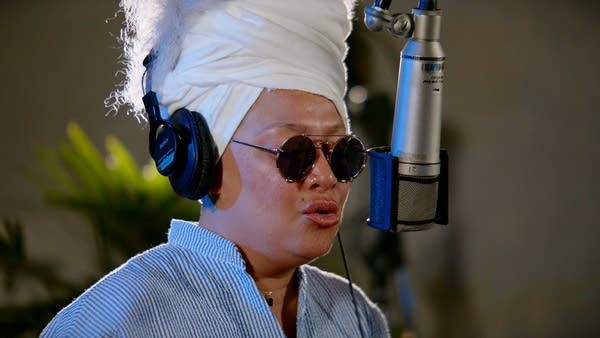 A woman sings into a microphone in a recording studio