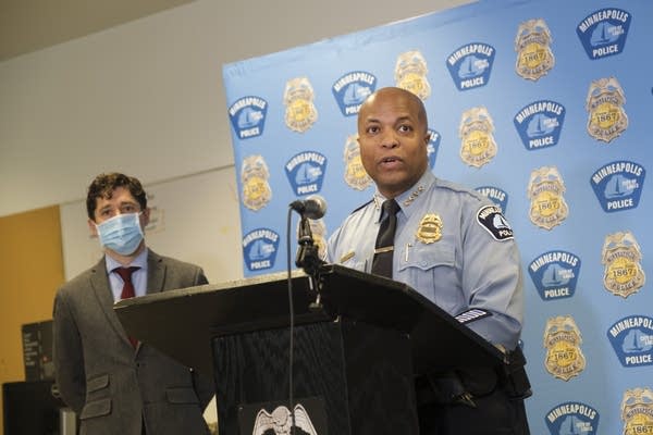 police chief speaks at podium with mayor behind him