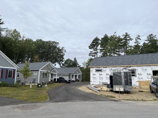 A house under construction next to several completed homes.