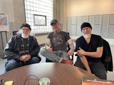 Three men wearing hats sit at a round table.