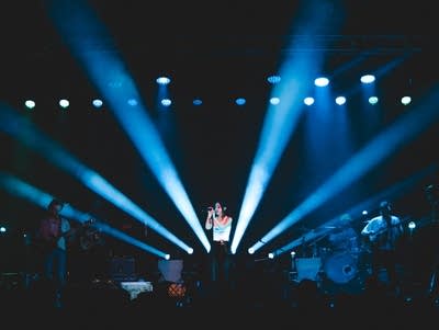 A woman sings into a microphone on a lighted stage.