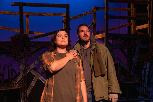 Two people stand on a stage.