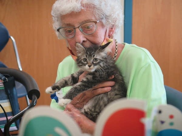 A old lady holds a kitten.