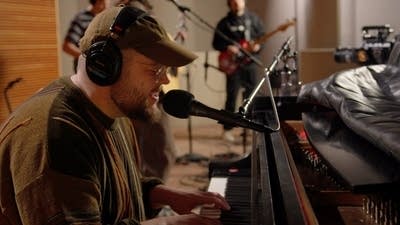 A musician sings and plays piano in a recording studio