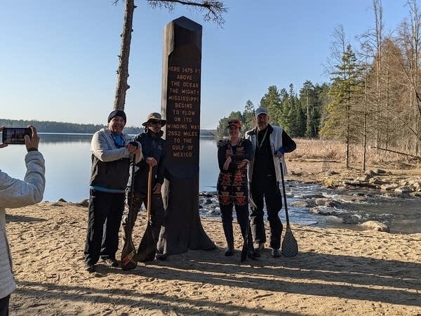 A group of four stand next to a sign