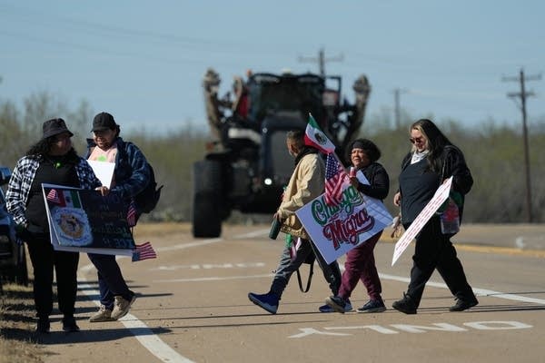 Protesters carry signs and flags.
