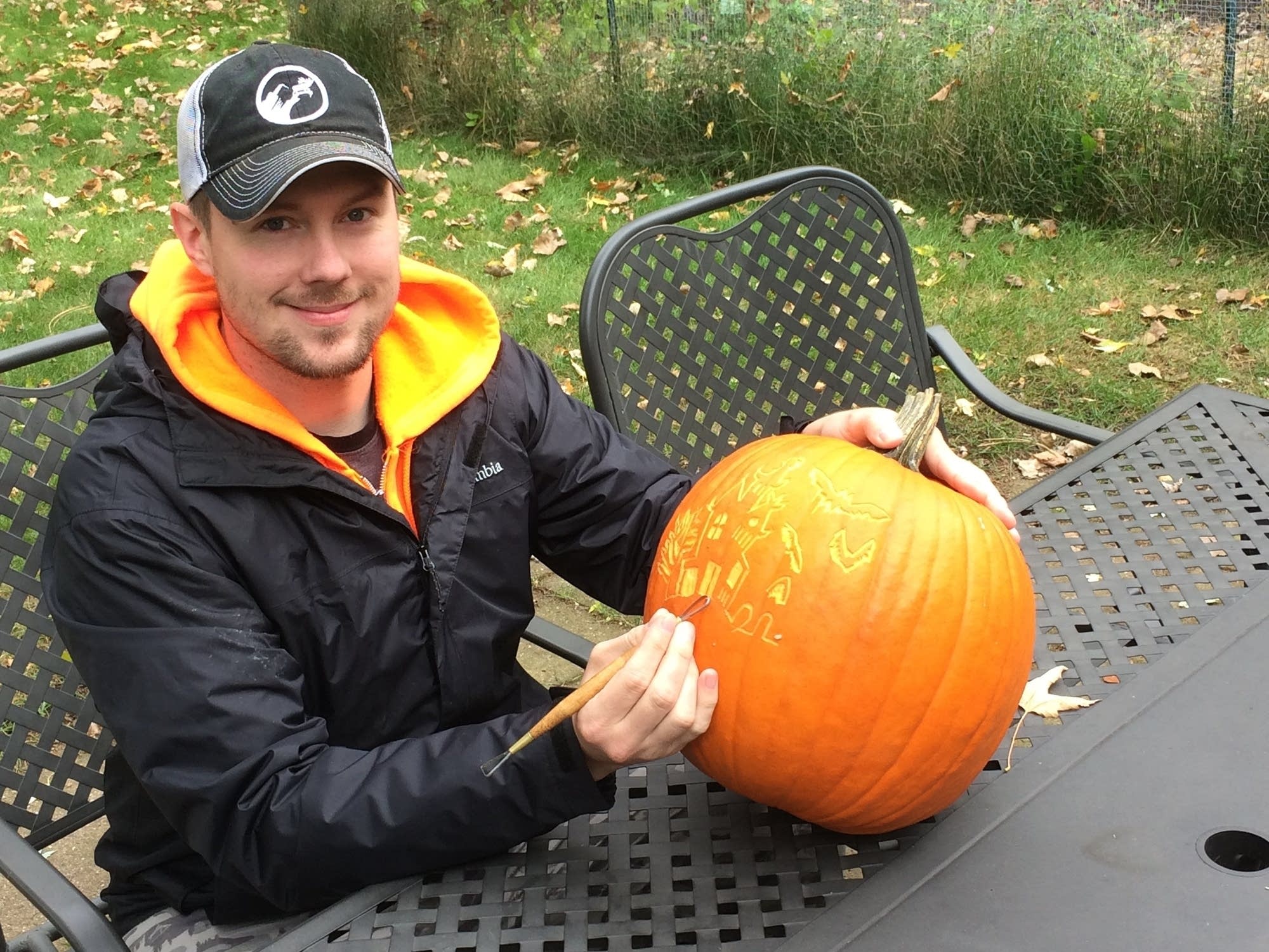 Ryan Lisson poses with a pumpkin as he completes a surface carving on it.