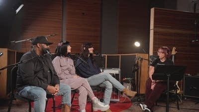 Four people have a conversation in a recording studio