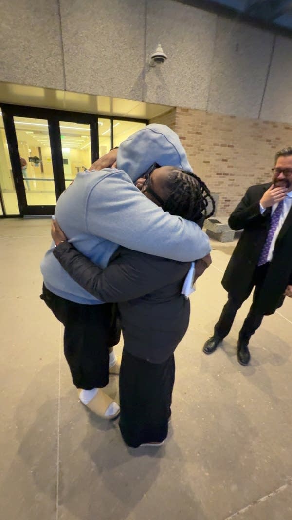 A man and woman embrace outside of a government building.