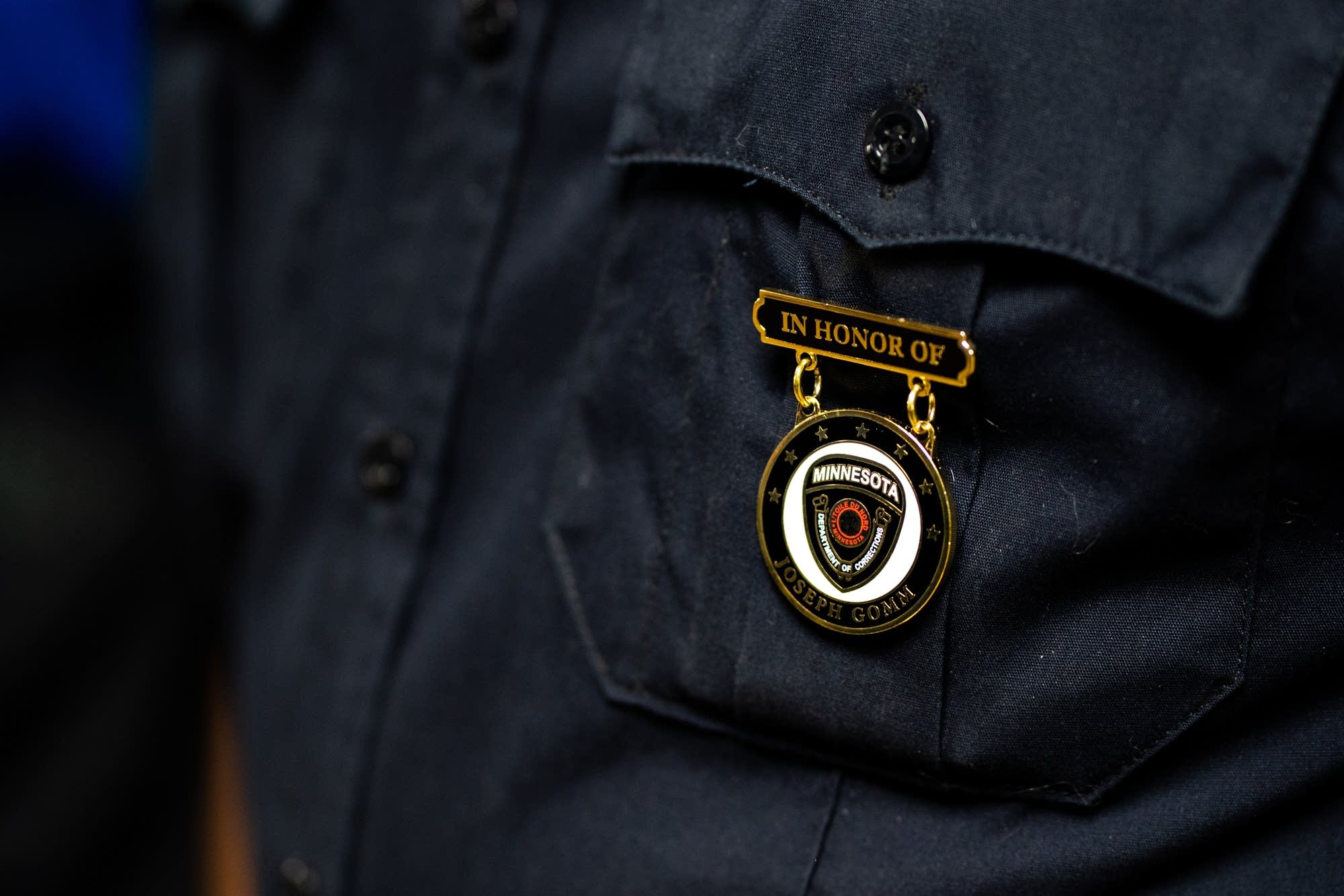 A corrections officer wears a pin commemorating Joseph Gomm.
