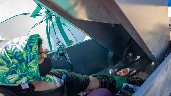 Two activists sit chained together around construction equipment.