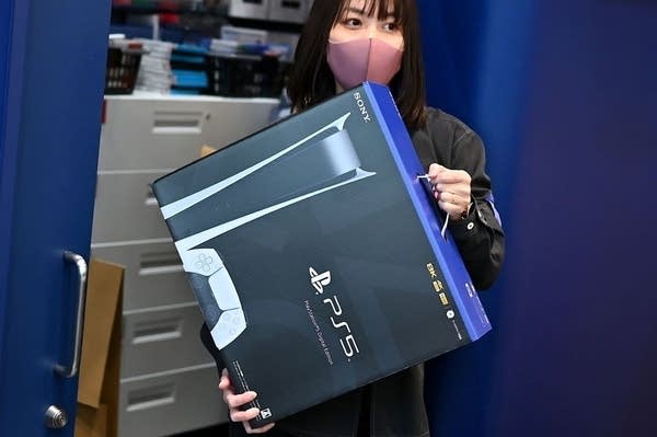 An employee prepares the new Sony PlayStation 5 gaming console for a customer on the first day of its launch, at an electronics shop in Kawasaki, Kanagawa prefecture on November 12, 2020.