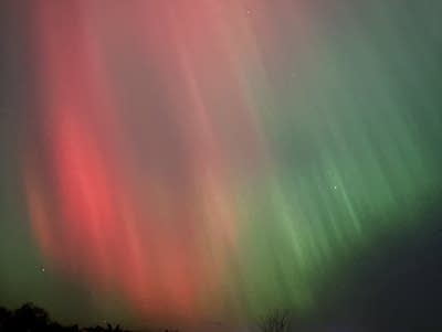 Green and red aurora lights in the night sky.