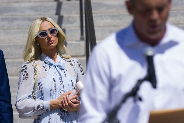 A woman in sunglasses walks down a flight of stairs.