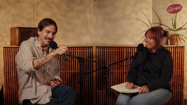 Two people have a conversation in a recording studio