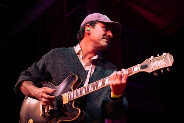 Man playing guitar and smiling on stage