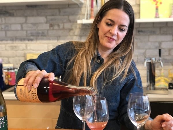 A woman pours a bottle of non-alcoholic spirits