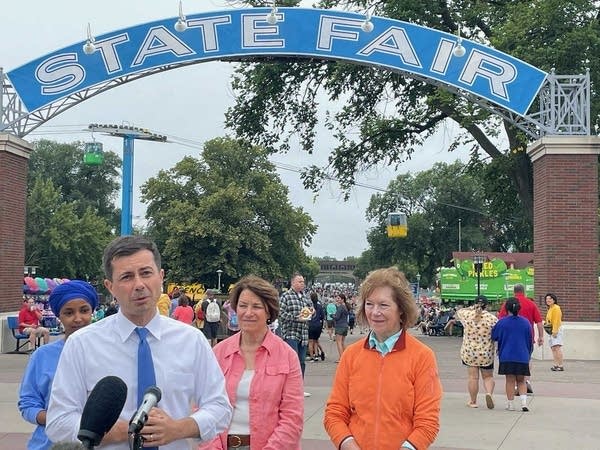 A man and three women in front of a State Fair gate