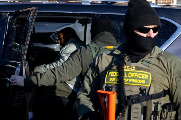 A Black man gets into a federal vehicle