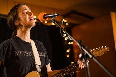 A woman sings and plays guitar in a small music venue